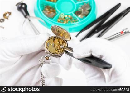 watchmaker workshop - adjusting of brass pocket watch by tweezers
