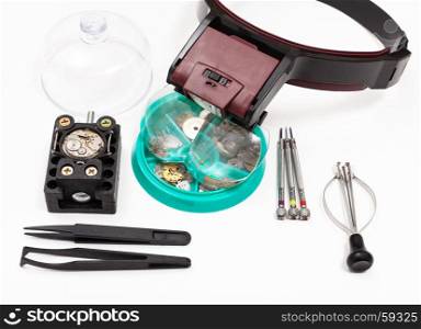 watchmaker workshop - kit of tools with head-mounted magnifier and spare parts for repairing mechanical watch on white background