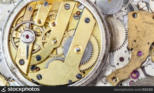watchmaker workshop - open brass mechanical watch on heap of clock spare parts