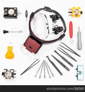 watchmaker workshop - top view of various items for repairing watch on white background
