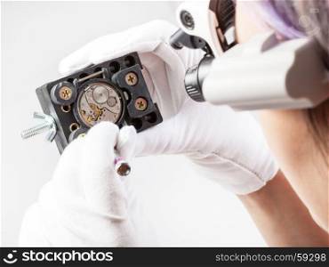 watchmaker workshop - watchmaker in head-mounted lenses repairs old mechanical wristwatch with screwdriver
