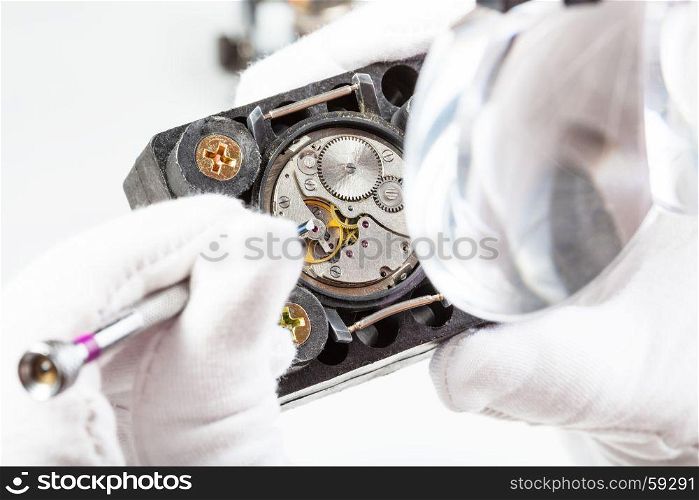 watchmaker workshop - watchmaker in head-mounted magnifier adjusts old watch with screwdriver