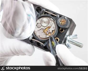 watchmaker workshop - watchmaker in head-mounted magnifier repairs old mechanical wristwatch with tweezers