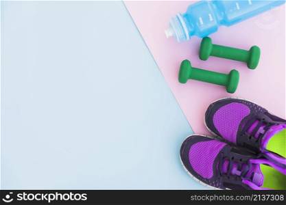 water bottle sport shoes dumbbells pink backdrop blue background