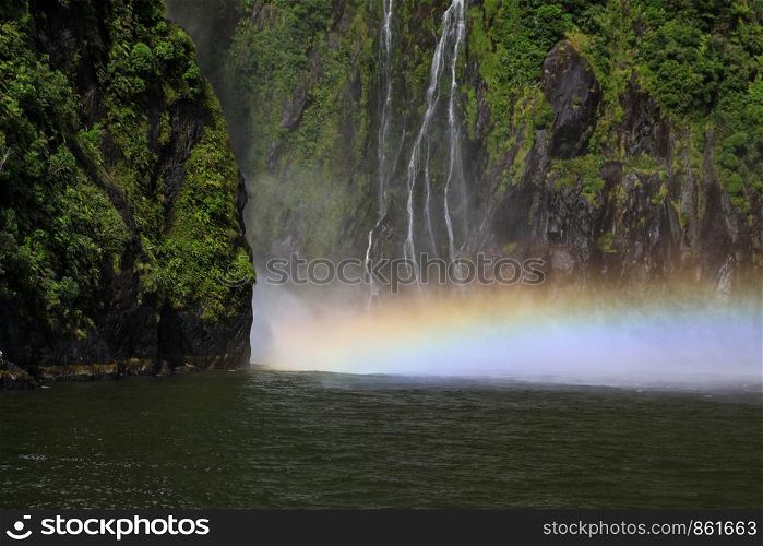 Water crashes into lake with rainbow in water vapor