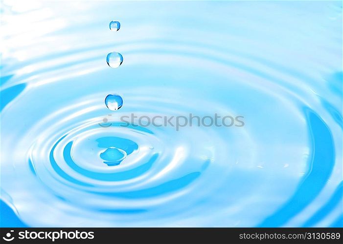 Water drop in rippled liquid close-up