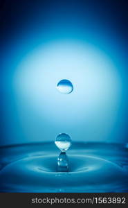 Water drop splashing into a surface blue background. Water drop