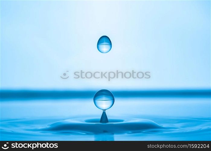 Water drop splashing into blue water surface. Health and purity concept. Water drop splashing into blue water surface