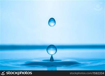 Water drop splashing into blue water surface. Health and purity concept. Water drop splashing into blue water surface