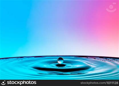Water droplets off the surface into a circle and a colorful background.