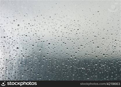 Water droplets on a transparent surface. On the background the blurry objects