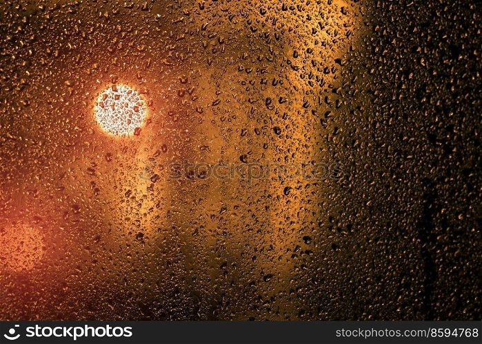 Water droplets on a window with city lights in the background in the evening