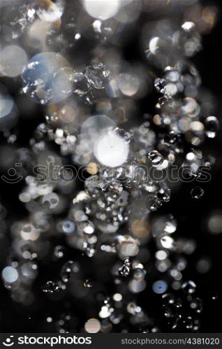 water drops fly in the air with defocused lights on background