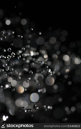 water drops fly in the air with defocused lights on background