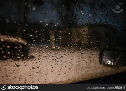 Water drops on car side glass in dusk