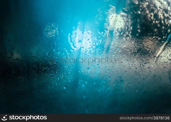 Water drops on car side glass in dusk and bokeh lights