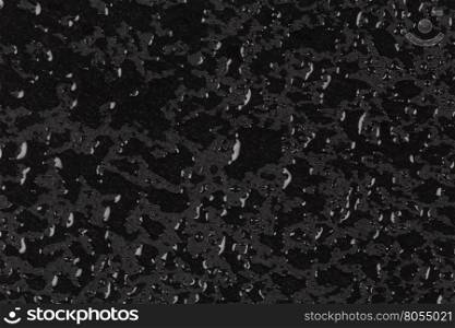 Water drops on dark stone rock surface of basalt or granite