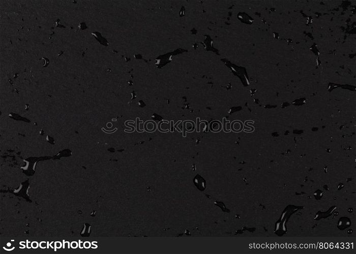 Water drops on dark stone rock surface of basalt or granite