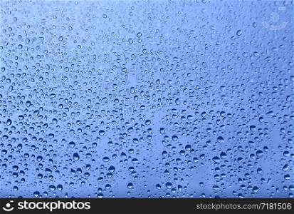 Water drops on glass, close-up natural blue texture