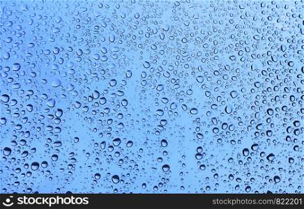 Water drops on glass, close-up natural blue texture
