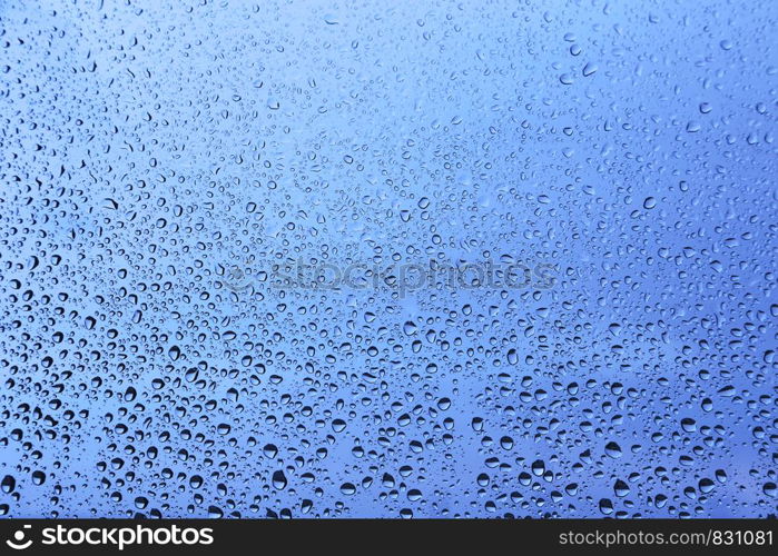 Water drops on glass, closeup blue natural background