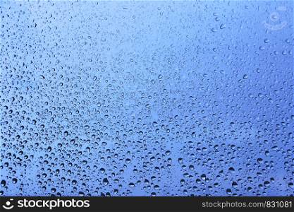 Water drops on glass, closeup blue natural background