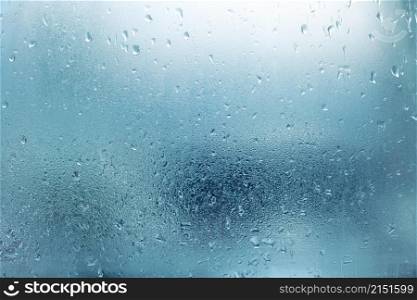 Water drops on glass window. Blue wet abstract background.