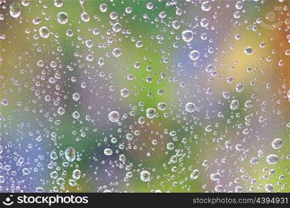 Water drops on glass window with nature in background