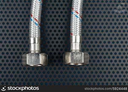 Water flexible hose in metallic braiding on a dark background