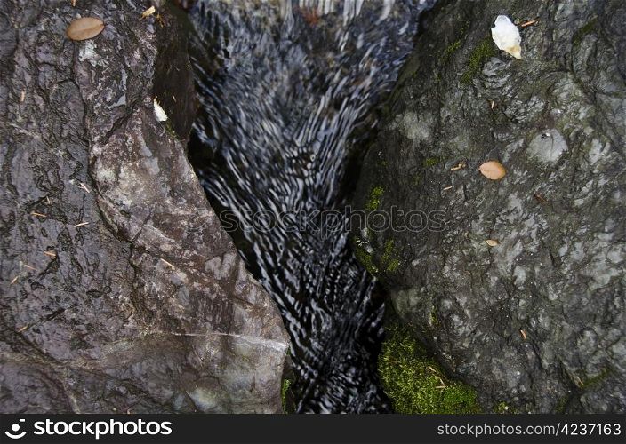 Water flowing in between rocks. Small water stream in between two rocks in autumn