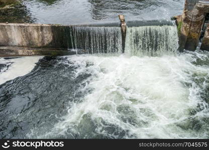 Water flows over a wall on the Tumwater River in Tumerwater, Washington.