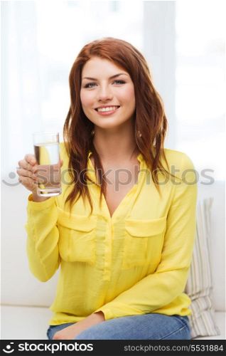 water, healthcare and happiness concept - smiling teenager with glass of water at home