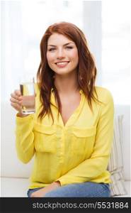 water, healthcare and happiness concept - smiling teenager with glass of water at home