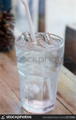 water in glass with ice and drinking straw on table. water in glass with ice on table
