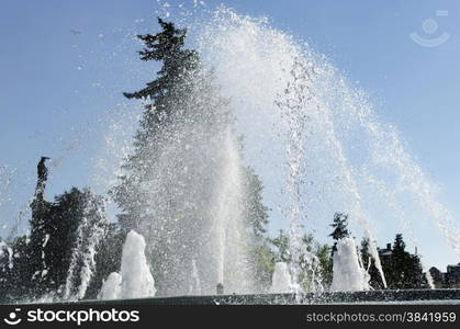 Water jet in a city park fountain with clear blue sky as background