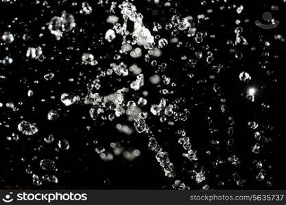 Water levitation. Bright drops flying in the air on black background