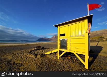 water lifeguard chair cabin red flag in spain lanzarote rock stone sky cloud beach musk pond coastline and summer