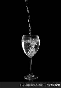 Water poured into glass of wine. Isolate on black.
