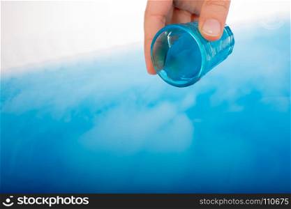 Water pouring down out of blue color glass in hand