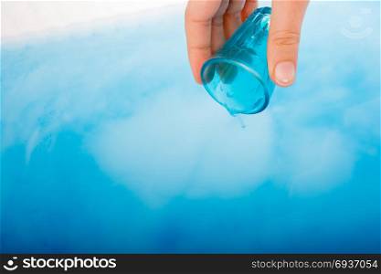 Water pouring down out of blue color glass in hand