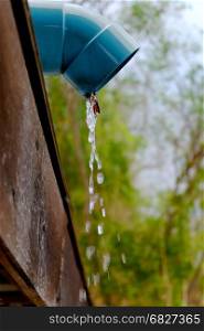 Water pouring from roof rain gutter downspout.