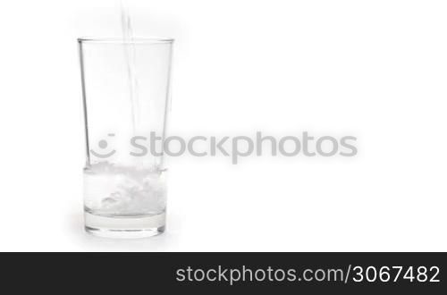 Water pours in glass with ice isolated on white background.