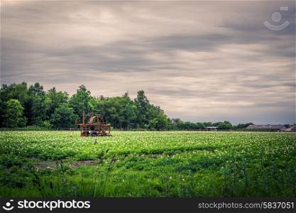 Water pump on a green field in dark cloudy weather