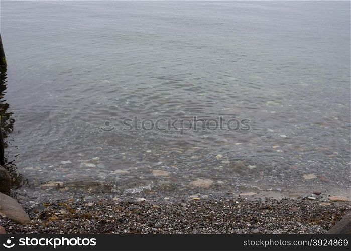 Water ripples on coast with pebble stones. Water ripples on beach with small pebble stones