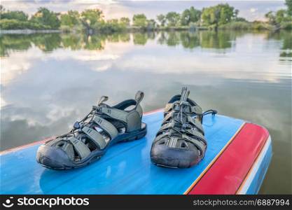 water sandals on a deck of stand up paddleboard, late summer lake scenery