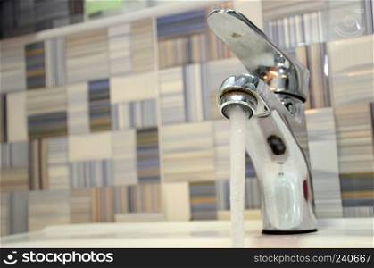 Water tap faucet with flowing water in a bathroom