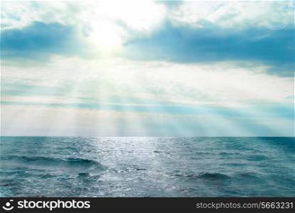 Water, waves and clouds. Sunset above the sea with sunbeams.