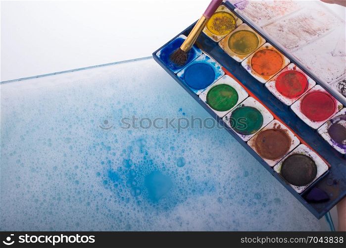 Watercolor paint dissolving in water covered with foam