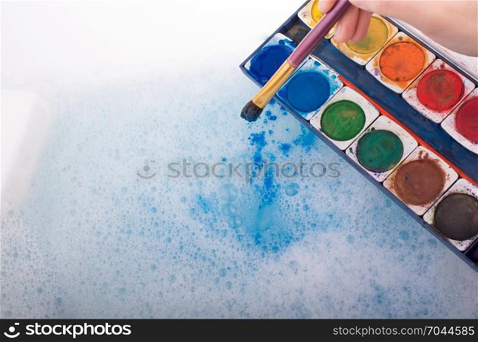 Watercolor paint dissolving in water covered with foam