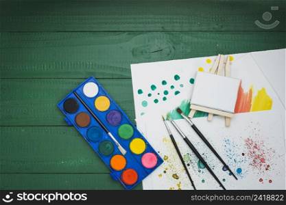 watercolor palette paint brushes mini easel hand drawn paper green desk